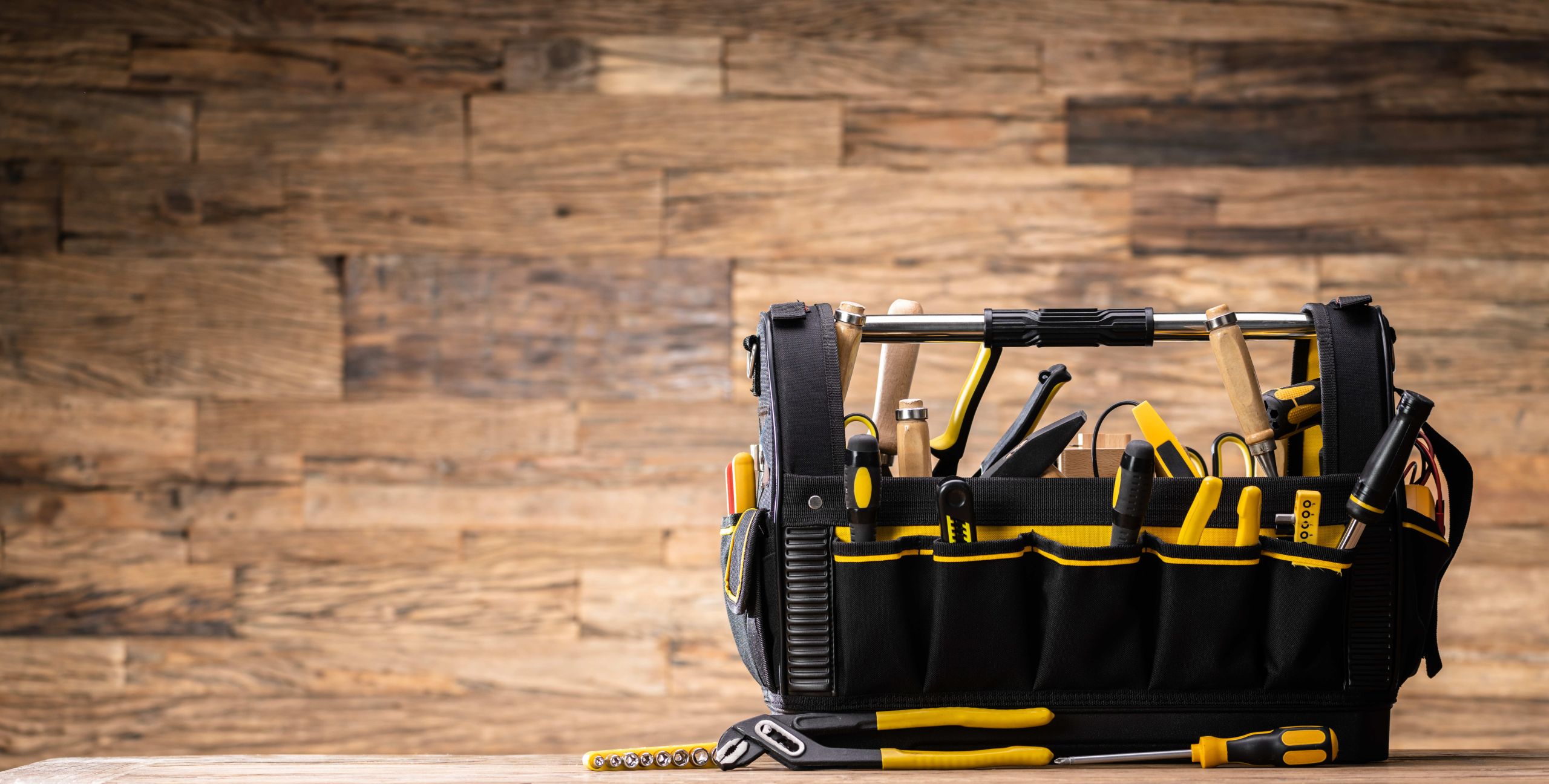 A buildings toolkit sitting on top of a table, with a wooden panel wall in the background